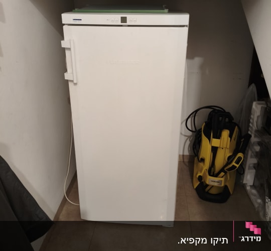 מקרר לבן עם מכשיר ניקוי צהוב לידו